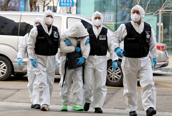 A Chinese man who escaped a state-run quarantine facility in Incheon on Tuesday night after testing positive for the coronavirus, center, is escorted back to the facility on Thursday. Police nabbed the suspect at a hotel in central Seoul. [YONHAP]