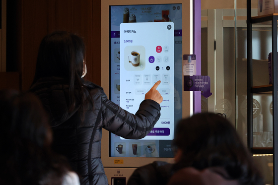 A customer orders coffee from a kiosk at a coffee shop in Seoul on Dec. 28, 2022. [NEWS1] 