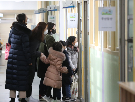 First grade students and their guardians peek into a classroom in Mapo District, western Seoul, on Jan. 4. [NEWS1] 