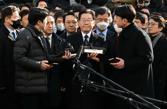 Democratic Party leader Lee Jae-myung before making his statement before entering the prosecutors’ office for investigation in Suwon, Gyeonggi, Tuesday while being surrounded by other DP lawmakers. Lee is being investigated for a quid pro quo when he served as mayor of Seongnam city. [YONHAP] 