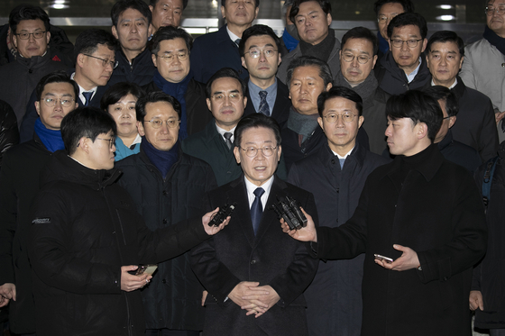 Democratic Party chairman Lee Jae-myung making a statement after 12 hours of questioning by the Suwon Prosecutors' Office on Tuesday while being surrounded by DP lawmakers. [YONHAP]