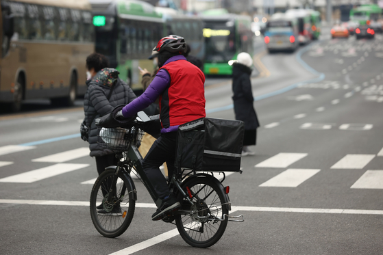 A delivery worker crosses a street in Seoul on Jan. 5. [YONHAP]