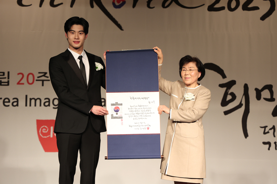 Swimmer Hwang Sun-woo, left, and Choi Jung-hwa, president of the Corea Image Communication Institute, hold up an award during the Korea Image Awards 2023 on Wednesday evening. Hwang was given the Korea Image Budding Youth Award. [CICI]