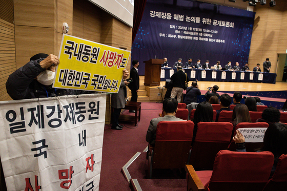 A participant holds up a sign at a hearing hosted by the Foreign Ministry at the National Assembly in Seoul on Thursday to discuss possible solutions to the forced labor issue between Japan and Korea. [NEWS1]