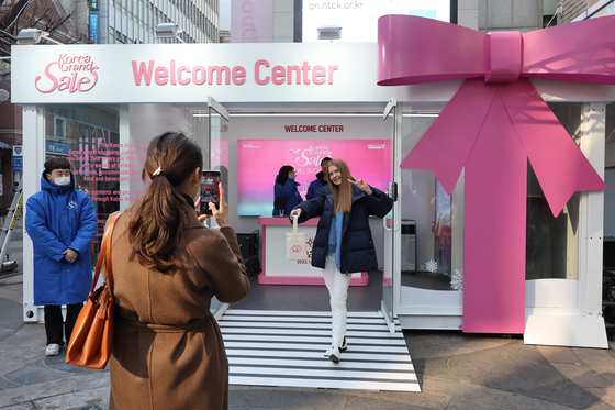 Foreign tourists take a photo in front of the Welcome Center for the Korea Grand Sale 2023 in Seoul's downtown shopping mecca Myeongdong on Thursday. Hundreds of businesses, including airline companies, hotels and restaurants, are participating in the online and offline campaign, which will continue until Feb. 28. [YONHAP]