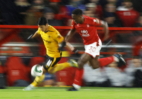 Wolverhampton Wanderers' Hwang Hee-chan in action with Nottingham Forest's Willy Boly during a Carabao Cup quarterfinal at City Ground in Nottingham on Wednesday.  [REUTERS/YONHAP]