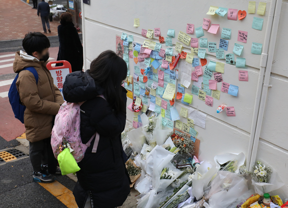 Students at Eonbuk Elementary School gaze at the notes mourning the death of Lee Dong-won at a memorial set up at the accident site on Dec. 13. [NEWS1]