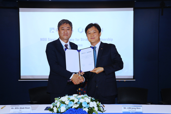 Kosign CEO Seol Wook-hwan, left, and Lim Jong-won, senior director of PPCBank, pose for a photo during a signing ceremony held in Phnom Penh on Dec. 29. [WEBCASH GROUP]