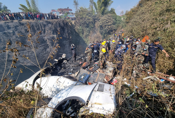Rescue teams work to retrieve bodies at the site of the crash of an aircraft carrying 72 people in Pokhara in western Nepal on Sunday. [REUTERS/YONHAP]