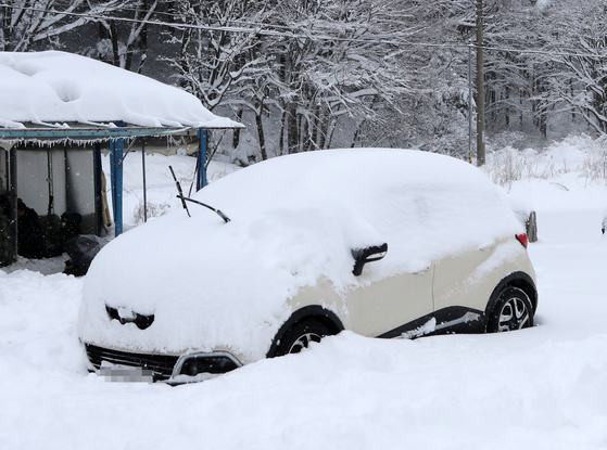 A car is covered in thick snow in Pyeongchang, Gangwon on Sunday. [YONHAP]