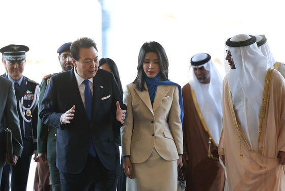 President Yoon Suk Yeol, left, accompanied by first lady Kim Keon Hee, center, speaks with United Arab Emirates (UAE) officials after arriving at Abu Dhabi International Airport in Abu Dhabi, kicking off a state visit Saturday. [YONHAP]