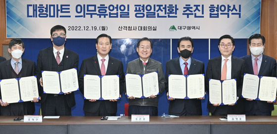 Daegu Mayor Hong Joon-pyo, fourth from right, and distribution industry officials pose at Daegu City Hall after signing an agreement on changing the mandatory super supermarket closing day on Dec. 19, 2022. [NEWS1]