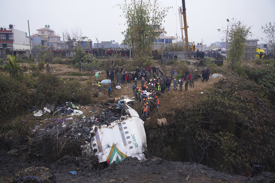 A rescue team works to recover the body of a victim from the site of the crash of a Yeti Airlines plane in Pokhara, Nepal on Monday. [AP/YONHAP]