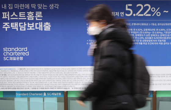 A person walks past a banner promoting loans in front of a bank in Seoul on Jan. 17. The Cost of Fund Index (Cofix), which is the reference rate for variable-rate mortgages, fell for the first time in 11 months to 4.29 percent in December. [YONHAP]