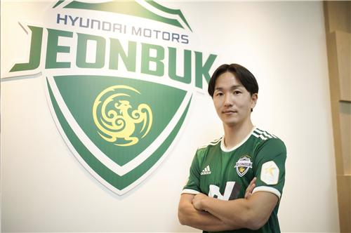 Jun Amano poses next to the Jeonbuk Hyundai Motors logo after joining the club on loan on Jan. 5.  [YONHAP]