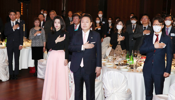 President Yoon Suk Yeol, center, and first lady Kim Keon Hee salute the Korean national flag at a dinner with Korean residents in Switzerland at a hotel in Zurich on Tuesday evening. [JOINT PRESS CORPS] 