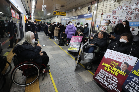 Members of the Solidarity Against Disability Discrimination (SADD) hold signs urging the government to increase spending on mobility for disabled people in Hyehwa Station, central Seoul, on Thursday morning. [YONHAP]