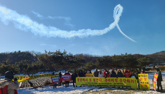 A Black Eagles aircraft somersaults above people protesting against the noise caused by the Korea Air Force’s aerobatic flight squadron in Hoengseong County, Gangwon, on Wednesday. The field in which the protestors held a press conference is where a KA-1 light attack aircraft crashed last month when it was dispatched to encounter a North Korean drone. [YONHAP]