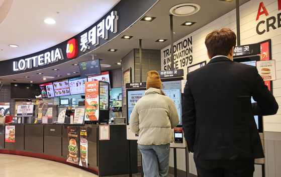 Customers order at a kiosk at a Lotteria branch in Seoul on Thursday. Lotteria said that day that it will raise its burger prices by 5.1 percent on average starting Feb. 2, due to rising logistics and labor costs. [YONHAP]