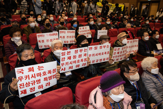 Forced labor victims and their relatives attend a forum hosted by the Foreign Ministry in Seoul on Jan. 12. Some are holding signs calling for an apology from the Japanese government. [NEWS1] 