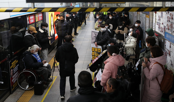 Members of the Solidarity Against Disability Discrimination (SADD) hold signs urging the government to increase spending on mobility for disabled people in Hyehwa Station, central Seoul, on Wednesday morning. [NEWS1]