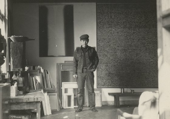 Yun Hyong-keun at his atelier after his teacher Kim Whan-ki passed away in 1974. The painting on the left is Yun's ″Umber-blue″ (1976-67) [NATIONAL MUSEUM OF MODERN ARTS]