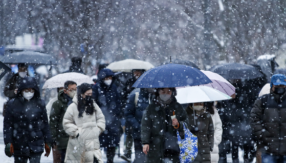 People are on their way to work on Thursday morning in Jongno District, central Seoul, as snow falls heavily in the area. [NEWS1]
