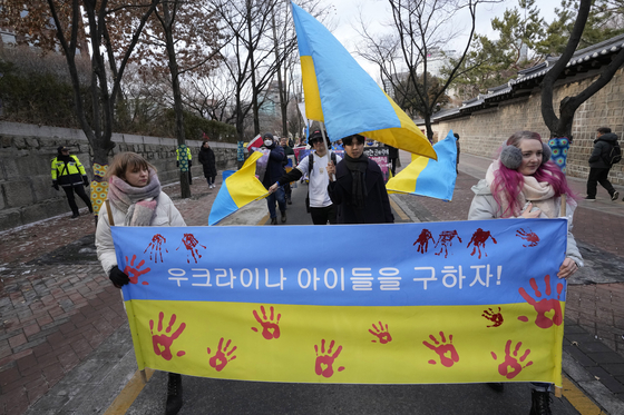 People march during a rally protesting Russia's invasion of Ukraine, near the Russian Embassy in central Seoul on Sunday, holding a banner that reads, ″Let's save Ukrainian children!″ [AP/YONHAP] 