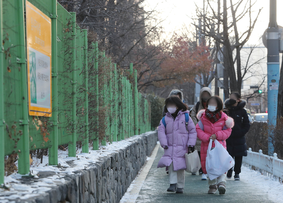 Students walk to school in a neighborhood in Seoul last Friday. Starting Monday, the indoor mask mandate will be lifted across all indoor facilities except on public transportation and in medical facilities such as hospitals. [NEWS1]