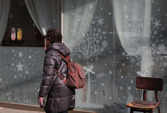 A passerby walks by a cafe with its windows covered with bubble wrap to reduce heat loss, in Seoul on Sunday. The sharp hike in gas prices is hitting Koreans hard as they get their first household gas bills of the winter season. [YONHAP]