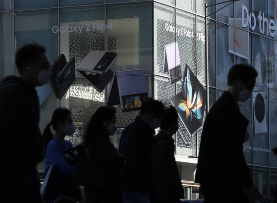 Passersby walk by a Samsung Electronics retail shop in Seoul. [News1]