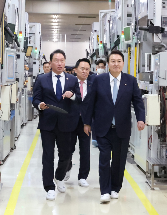 President Yoon Suk Yeol, right, inspects a SK siltron wafer production facility in Gumi, North Gyeongsang, with SK Inc. Chairman Chey Tae-won on Wednesday. Yoon's visit comes after the chip wafer company announced a 1.2-trillion-won ($975 million) investment to ramp up the facility's capacity. [YONHAP]