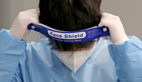 A medical staff puts on a face shield at a Covid-19 testing center in Seoul Station on Monday. [NEWS1]