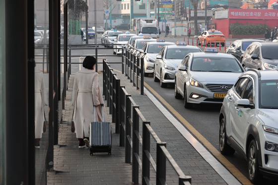 A customer walks to grab a taxi in front of Seoul Station on Wednesday, the first time in four years the base fare for taxis in Seoul were raised, going from 3,800 won to 4,800 won ($3.10 to $3.90). [YONHAP]