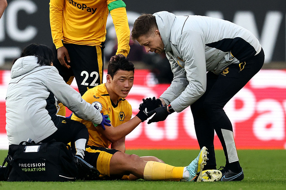 Wolverhampton Wanderers' Hwang Hee-chan receives medical attention during a Premier League match against Liverpool at the Molineux stadium in Wolverhampton, England on Saturday.  [AFP/YONHAP]