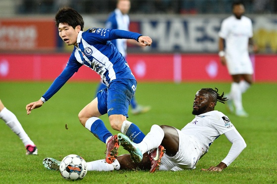 K.A.A. Gent's Hong Hyun-seok, left, fights for the ball with Genk's Tolu Arokodare during a Belgian Pro League match in Ghent on Sunday.  [AFP/YONHAP]