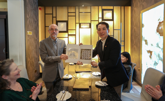 Veterans Minister Park Min-shik, right, handing postal stamps commemorating Ernest Bethell, who reported on Japan's misdeeds against Korea during its colonial rule, to his grandson as they meet at a restaurant in London on Feb. 3. [MINSTRY OF PATRIOTS AND VETERANS AFFAIRS]