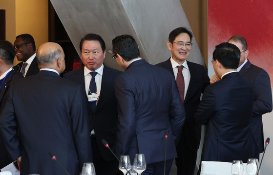 Samsung Electronics Executive Chairman Lee Jae-yong, right, and SK Chairman Chey Tae-won, left, chat with global business leaders at the Global Business Leadership Luncheon in Davos, Switzerland Wednesday. [JOINT PRESS CORPS]