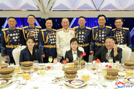 North Korean leader Kim Jong-un (right), his daughter Kim Ju-ae (center) and his wife Ri Sol-ju (left) sit at a banquet celebrating the 75th anniversary of the founding of the Korean People's Army (KPA), with KPA generals standing behind them in this photo released by the Korean Central News Agency on Wednesday. [YONHAP]