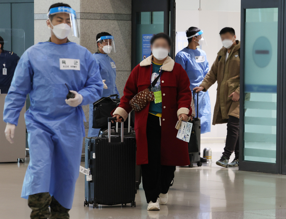A Korean quarantine official escorts travelers from China for PCR testing at Incheon International Airport on Sunday.. [YONHAP]