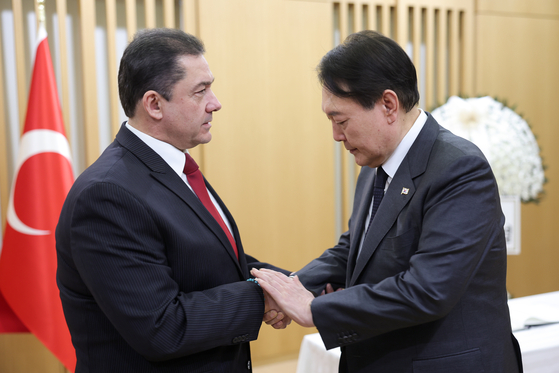 President Yoon Suk Yeol, right, expresses his condolences to Turkish Ambassador to Korea Murat Tamer after the devastating earthquake in Turkey earlier this week at the Turkish Embassy in Seoul on Thursday. [PRESIDENTIAL OFFICE]