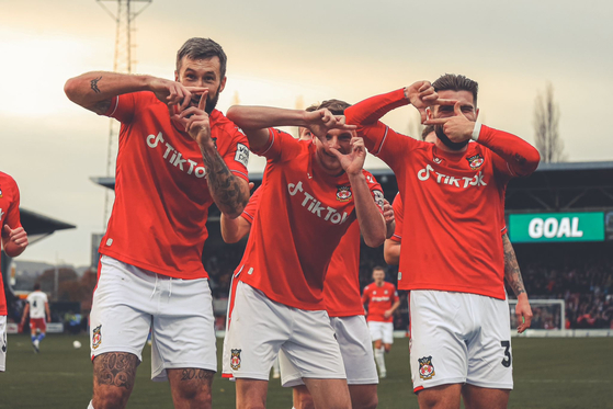 Wrexham players celebrate with Son Heung-min’s camera celebration during an FA Cup game against Sheffield United at The Racecourse Ground in Wrexham, Wales on Jan. 29 in a photo posted to the club’s official Twitter page. [SCREEN CAPTURE]
