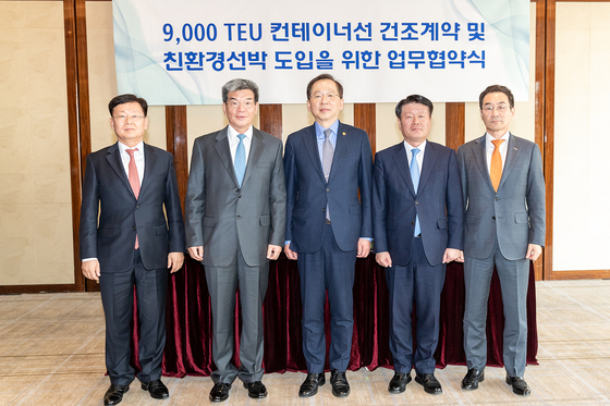 Officials, including Minister of Oceans and Fisheries Cho Seung-hwan, center, and CEO of HMM Kim Kyung-bae, second from right, pose for a picture at a signing ceremony for the container ship construction contract at the Westin Josun Hotel in central Seoul on Tuesday. [HMM]