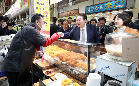 President Yoon Suk Yeol, center, accompanied by SMEs and Startups Minister Lee Young, shakes hands with a shopkeeper during a visit to a traditional market in Cheongju, North Chungcheong, on Feb. 14. [YONHAP]