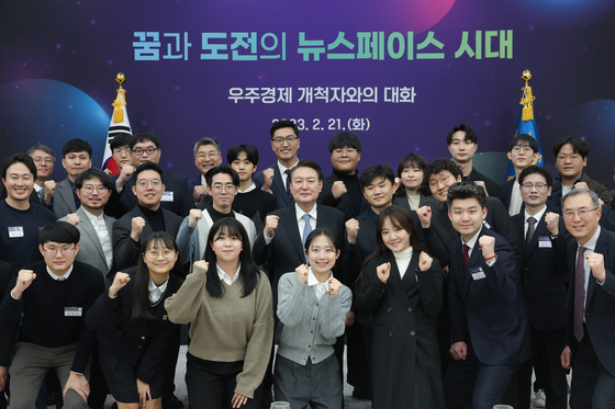 President Yoon Suk-yeol, center, takes a commemorative photo with participants of a luncheon meeting of space economy pioneers, along with singer Younha, front row third from right, Tuesday at the Yongsan presidential office in central Seoul. [PRESIDENTIAL OFFICE]