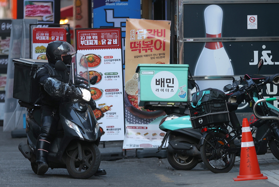 A delivery rider parks the motorcycle in front of a restaurant in Seoul on Tuesday [YONHAP]