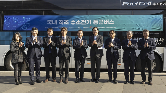 Attendees of a liquid hydrogen forum held in Incheon, Wednesday, pose for a photo in front of Korea's first fuel cell electric commute bus. [SK E&S]
