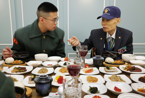 A marine, left, having lunch with a Korean War veteran during an event held at the National Agricultural Cooperative Federation’s headquarters in Jung District, central Seoul, Wednesday. The event, jointly organized by the farmer cooperative and the Ministry of Patriots and Veteran Affairs, commemorated the 70th anniversary of the Korean War armistice. The dishes included fresh produce grown in the demilitarized zone. [JOINT PRESS CORPS]