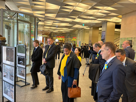 Ambassadors and diplomats in Seoul observe the photos taken in Ukraine in the past year during the Russian invasion of the country, at a photo exhibition organized by the Ukrainian Embassy in Seoul with the European Union Delegation in Seoul on Friday. [ESTHER CHUNG]