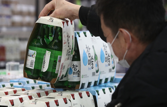 A customer picks up a soju pack at a discount store in Seoul on Tuesday. [NEWS1]
